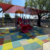 Playground with colorful rubber interlocking tiles providing safe slip resistant surfacing under slides and play equipment