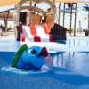 Splash pad water feature with dolphin spray on blue rubber safety surfacing designed for slip resistance in aquatic play areas