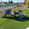 Commercial playground installed with SprintPlay Elite artificial turf surfacing and accessible play structures for children